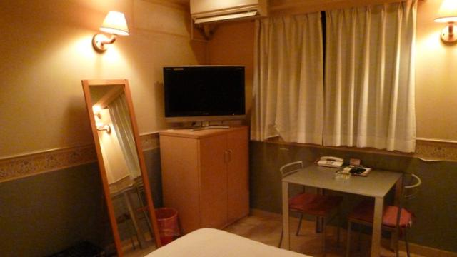 HOTEL K(新宿区/ラブホテル)の写真『305号室（ベッド頭から部屋奥方向。二人で落ち着いてご飯が食べられそうな大きさのテーブルがあります。椅子も2脚。TVの下に冷蔵庫があります）』by 格付屋