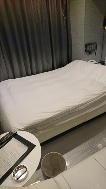 HOTEL THE HOTEL（ホテル　ザ・ホテル）(新宿区/ラブホテル)の写真『33号室 ソファーの上に乗って撮ったベッドの写真。手前にテーブルとゴミ箱。テーブル上に灰皿とライター、テレビのリモコン。ホテルについてのアンケート用紙』by なめろう