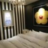 HOTEL G-Style(豊島区/ラブホテル)の写真『203号室 ベッド。分かりにくいが枕元奥の棚にある円形に見えるのがおそらく体験談に書いた腕を拘束した紐を結ぶ為の金具。反対側の壁にもあり。金具の横に電マの頭が見える。』by なめろう