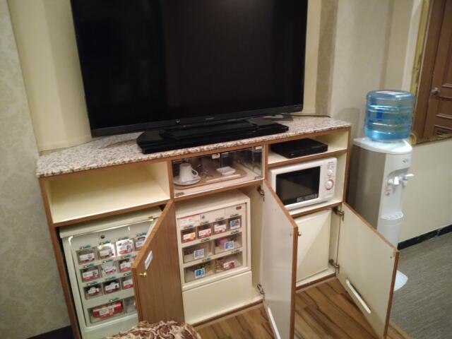 HOTEL CUE厚木(厚木市/ラブホテル)の写真『405号室 テレビの下に食器類と電子レンジ。その下に左から販売用の冷蔵庫が２つと持ち込み用の冷蔵庫。』by なめろう